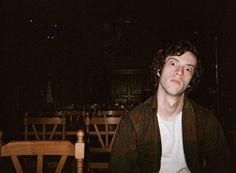 a young man sitting at a table in the dark