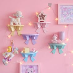 a pink wall with some little toys hanging on it's sides and lights strung from the ceiling