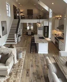 a large open concept kitchen and living room with stairs leading up to the second floor