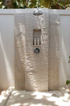 an outdoor shower in the middle of a patio with white walls and tile flooring