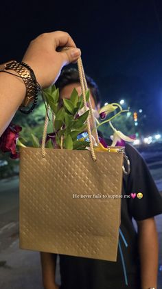 a person holding a brown bag with a plant in it