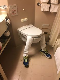 a person standing in front of a toilet with their legs wrapped around the seat and feet propped up