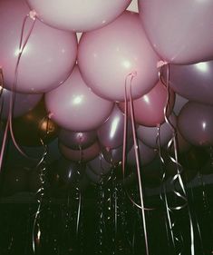 a bunch of pink and white balloons floating in the air