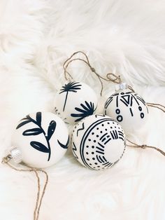 three ornaments with black and white designs on them sitting on a fur covered floor next to some string