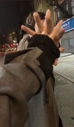 a person holding their hands up in the air on a city street at night time