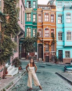 a woman standing in the middle of a street with many colorful buildings on both sides