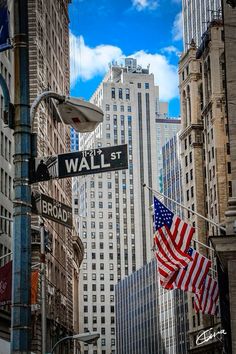 an american flag hanging from a street sign on wall street in new york city, usa