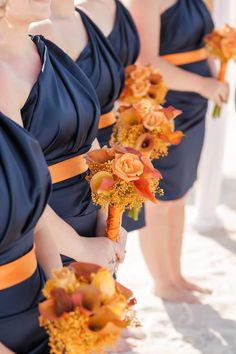 the bridesmaids are holding their bouquets in orange and brown colors, with one woman wearing a blue dress