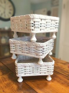 three white wicker baskets stacked on top of each other in front of a clock