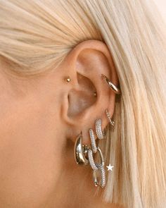 a woman with blonde hair is wearing three different ear piercings and one has two stars on it