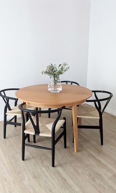 a wooden table with four chairs around it and a vase filled with flowers on top