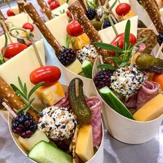 several different types of cheeses and vegetables in small trays with sticks sticking out of them