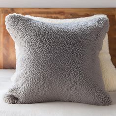 a gray pillow sitting on top of a bed