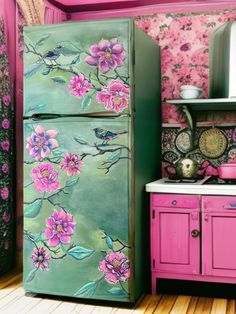 a green refrigerator with pink flowers painted on the doors and drawers next to a stove top oven