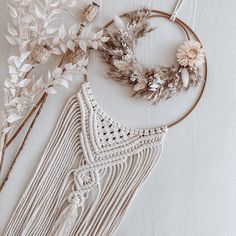 a white wall hanging next to some dried flowers