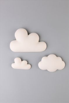 three white clouds sitting on top of a gray surface