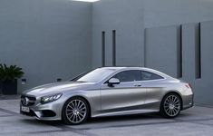 a silver mercedes cla parked in front of a building with grey walls and concrete flooring