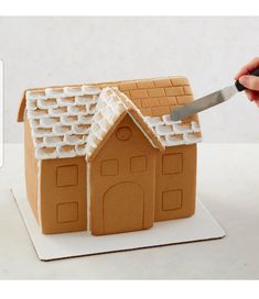 a person cutting into a ginger house with a knife