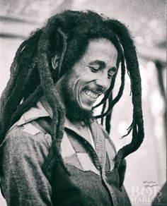 a man with dreadlocks smiling and looking at his cell phone