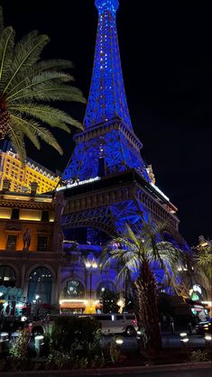 the eiffel tower lit up at night in paris, france with palm trees