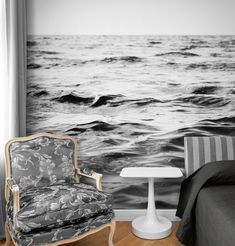 a bedroom with a chair, bed and wall mural in black and white colors on the walls