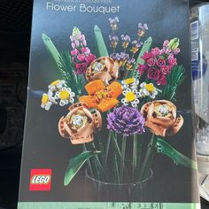 a book with flowers in it sitting on a wooden table next to a lego brick