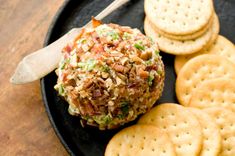 a black plate topped with crackers and a cheese ball