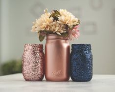 three different colored mason jars with flowers in them