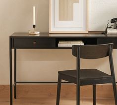 a black desk with a chair next to it and a framed photograph on the wall