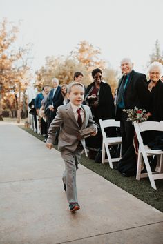 a little boy in a suit running down the aisle