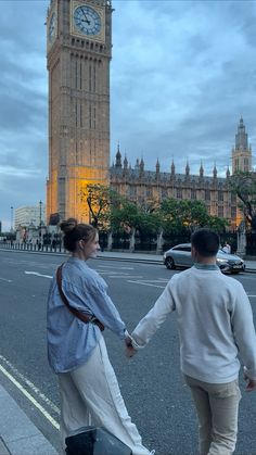 a man and woman holding hands in front of the big ben clock tower