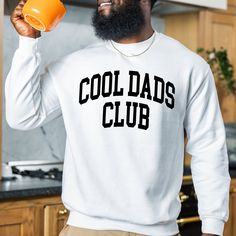 The "Cool Dads Club Sweatshirt" is a sturdy and warm sweatshirt bound to keep you warm in the colder months. A pre-shrunk, classic fit sweater made with love for you & your loved ones! Sweatshirt Details: * Gildan sweatshirt - unisex fit * 50% cotton, 50% polyester * Pre-shrunk * Classic fit with no center crease * 1x1 athletic rib knit collar with spandex * Air-jet spun yarn with a soft feel and reduced pilling * Double-needle stitched collar, shoulders, armholes, cuffs, and hem * Model is wear Cool Sweatshirt With Letter Print, White Graphic Print Sweatshirt For Father's Day, Father's Day White Graphic Print Sweatshirt, Casual Graphic Print Sweatshirt For Father's Day, Father's Day Casual Sweatshirt With Name Print, Father's Day Casual Graphic Sweatshirt, Dad Crewneck Sweatshirt, Father's Day Gift Crew Neck T-shirt, Dad Sweater