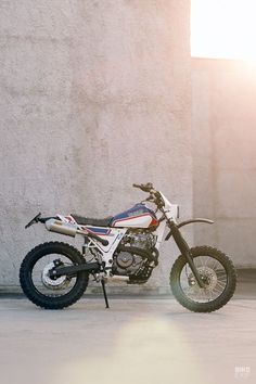 a dirt bike parked in front of a building with the sun shining down on it