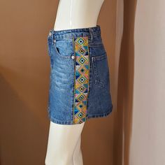 a mannequin wearing a denim skirt with multicolored patches on the side