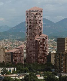 a tall building with lots of windows in the middle of it and mountains in the background