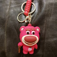 a pink bear keychain with a red cord hanging from it's side