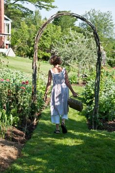 a woman walking down a path through a garden