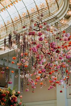 an elaborate chandelier with pink and red flowers hanging from it's ceiling