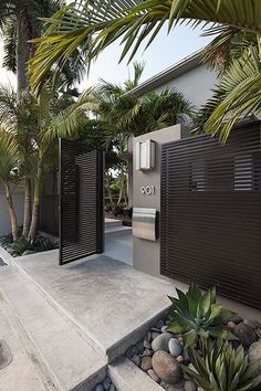 a modern house with palm trees in the front yard and an outdoor shower area on the other side