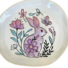 a white plate with a pink bunny and flowers painted on it