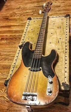 an old bass guitar sitting on top of a wooden table