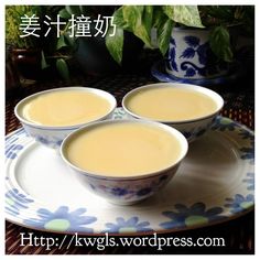 three bowls filled with liquid sitting on top of a white and blue plate next to a potted plant