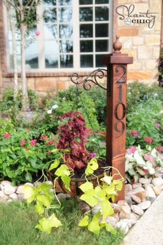 a wooden pole with a clock on it next to some flowers and plants in the background