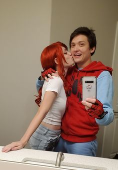 a man and woman kissing while taking a selfie in front of a bathroom mirror