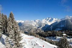 skiers are skiing down a snowy mountain with mountains in the backgrounnd