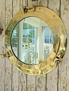 a round mirror hanging on the side of a wooden wall next to a window and door