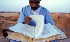 a man holding an open book in his hands and looking at the pages on it