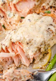 salmon and asparagus on a plate with cream sauce over the top, ready to be eaten