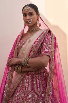 Rani pink lehenga with zardozi embroidery using silken threads, dabka, cutdana and sequins. Comes with embroidered blouse, one sheer dupatta and a contrast dupatta.
Component: 4
Pattern: Embroidered
Type Of Work: Zardozi, silken threads, dabka, cutdana and sequins
Neckline: Plunged V- Neck
Sleeve Type: Short
Fabric: Raw Silk
Color: Pink
Other Details: 
Leaf shaped neckline
Back cutout with tassel tie-up
Dupatta 1: Rani pink dupatta with embroidered borders
Dupatta: 2: Contrast dupatta with embro Pink Kundan Saree, Pink Kundan Traditional Wear For Reception, Pink Kundan Sets With Cutdana, Pink Gota Work Sets For Navratri, Pink Sets With Gota Work For Navratri, Pink Dori Work Chandbali Saree, Pink Dori Work Dupatta For Reception, Pink Kundan Anarkali Set For Designer Wear, Pink Dupatta With Dori Work For Reception