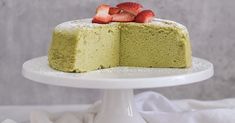 there is a green cake with strawberries on the top and one slice cut out